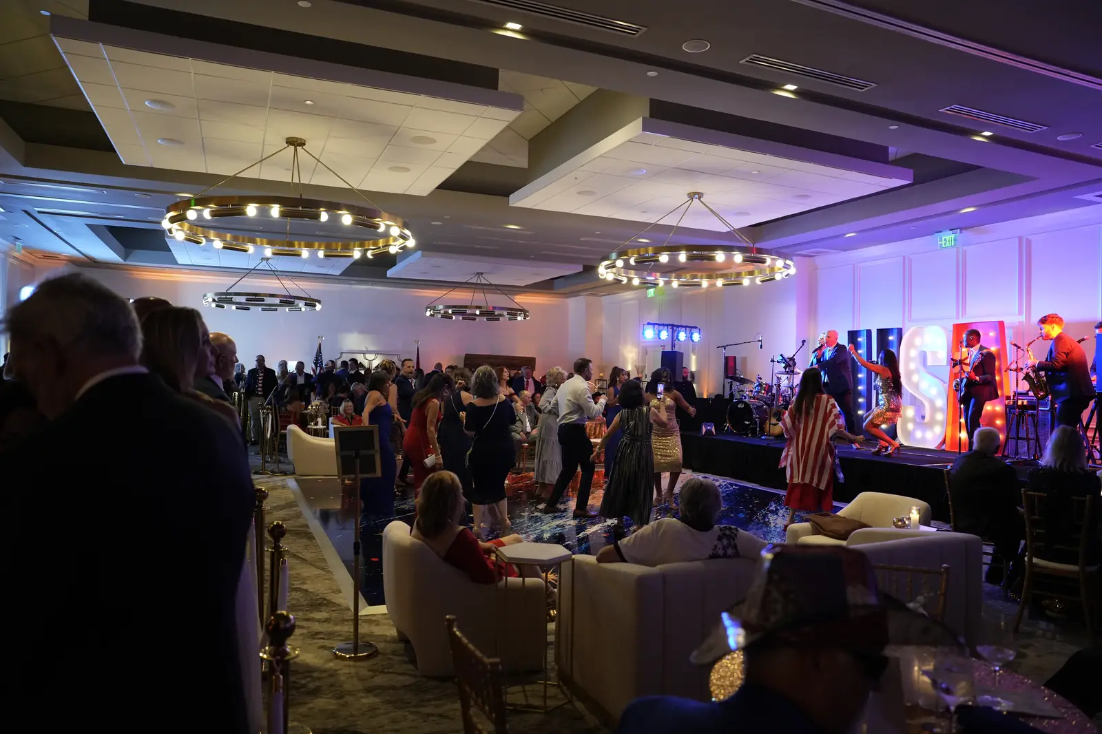 Gala guests dancing on the dance floor in the PGA National Resort ballroom while the band and singers perform in front of lit USA marquee letters