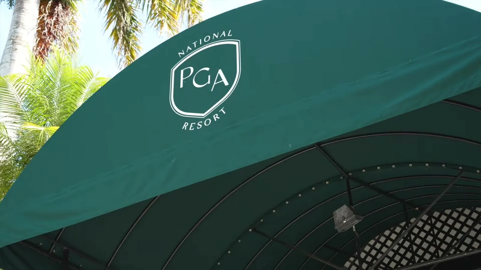 Green entrance canopy with the PGA National Resort logo, framed by palm trees, in Palm Beach Gardens, Florida