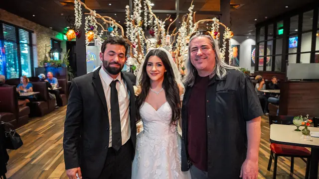 The couple with a guest at their wedding reception